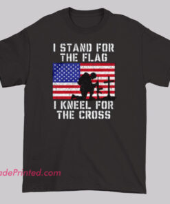 Black t-shirt with slogan “I STAND FOR THE FLAG I KNEEL FOR THE CROSS,” featuring silhouette of kneeling soldier before American flag and three crosses, blending faith and patriotism.